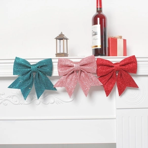 Glitter Christmas bows in teal, pink and red hanging on fireplace for festive decor