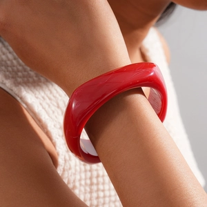 Close-up of red chunky resin bangle bracelet styled with a white knitted sleeve