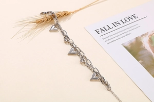 Detailed view of silver double-layered heart bracelet with wheat and card on warm background