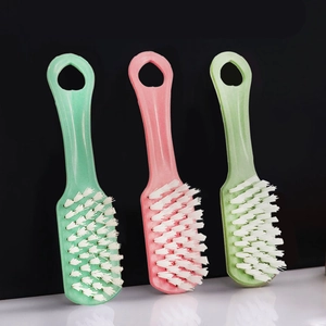 Three plastic shoe cleaning brushes in pink and green colors with soft white bristles