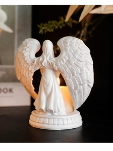 Detailed view of white praying angel candle holder wings with warm glowing candlelight