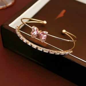 Close-up of gold double-layer bracelet featuring pink zircon bow and baguette-cut crystals