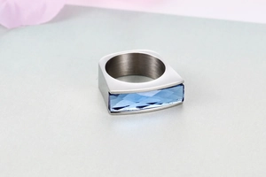 Close-up of a wide silver titanium ring featuring a faceted light blue rectangular gem