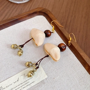 Detail of tiger eye stone earrings with wood beads and a golden acorn pendant