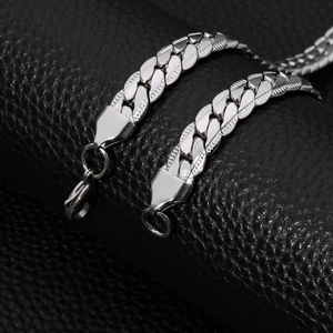 Macro shot of silver stainless steel Cuban chain link texture and clasp on black leather