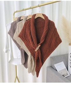 Close-up of knitted shawl with leather buckle fastener on a gold hanger