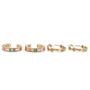 Close-up of gold geometric hoop earrings and rings with colorful baguette zircon stones