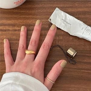Close-up of minimalist gold twisted rope ring and matte wavy band on wooden surface