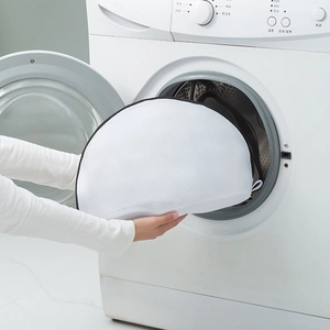 Mains plaçant un sac à linge en maille pour chaussures dans un lave-linge domestique