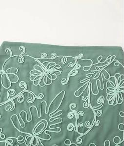 Detailed close-up of floral ribbon embroidery on green fabric showing exquisite needlework
