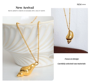 Detailed view of a gold conch pendant necklace on a ceramic bowl with hanging display