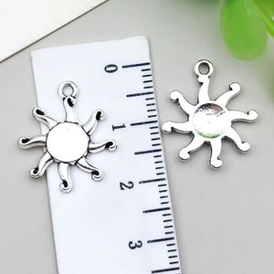 Detailed macro view of 3cm antique silver sun pendants with measurement ruler