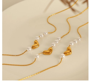 Vue détaillée de trois colliers à pendentif cœur doré avec d'élégantes perles blanches