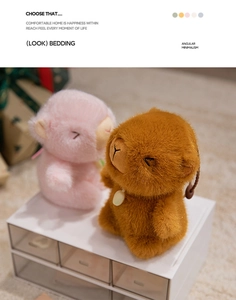 Close-up of pink and brown plush capybara keychains on a clean storage box