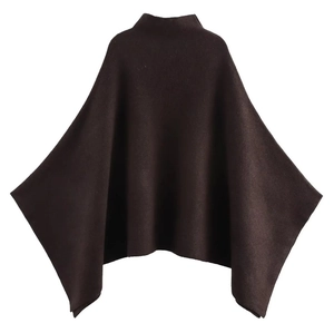 Detail view of dark brown knitted poncho featuring a standing collar and asymmetric hemline