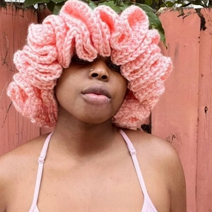 Detailed knit texture of pink ruffled beanie hat with layered oversized crochet design