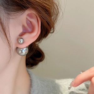 Close-up of double-sided silver pearl stud earrings worn by a model in a luxury style