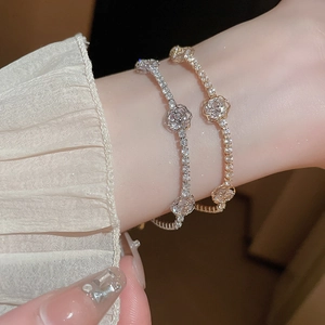 Détail de bracelets fleurs en zircon de luxe en or et argent portés au poignet