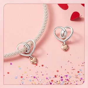 Close-up of S925 sterling silver heart charm bracelet and stud earrings on romantic background