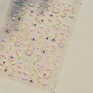 Detailed macro view of 3D embossed pink lily of the valley and bow nail art stickers