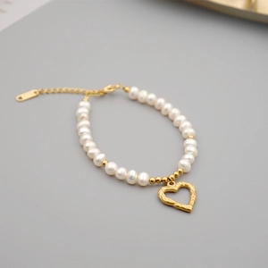 Elegant freshwater pearl bracelet with a textured gold heart pendant and adjustable chain