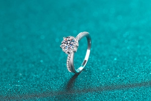 Macro shot of 1 carat round moissanite stone and silver ring band on blue background