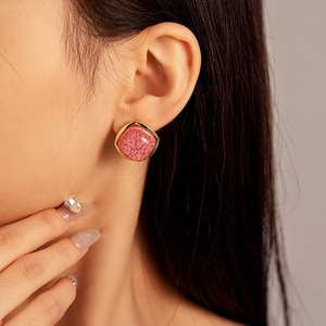 Close-up of vintage square pink resin stud earring with textured gold metal frame