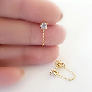 Close-up of gold chain earrings with sparkling round zircon and minimalist s925 silver needles