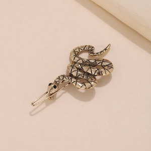 Antique bronze snake shaped metal hair clip with detailed textures on beige background