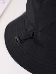 Detail of black sun hat featuring durable multi-stitch brim and adjustable windproof toggle