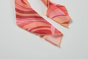 Detail shot of orange and pink geometric wavy pattern on lightweight silk-like scarf