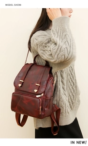 Detailansicht eines weinroten Vintage-Rucksacks mit goldenen Metallteilen am Model