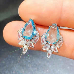 Macro view of blue pear-cut gemstone earrings with white zircon flower cluster details