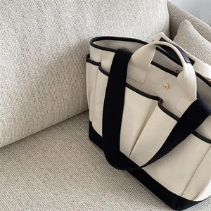 Detail of canvas diaper bag with side pockets, contrast trim and metal snap button