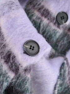 Macro shot of purple plaid wool coat fabric texture and black round resin button detail