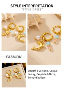 Detailed view of gold dolphin earrings with blue beads and pearls on a sandy surface