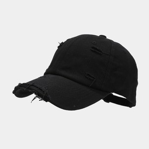 Close-up of distressed details and frayed edges on a black cotton twill baseball cap