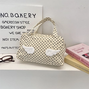 Detailed close-up of beige polka dot canvas toiletry bag with plush wing decorations