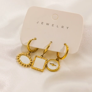 Dettaglio macro di tre orecchini placcati oro 14K con pendenti in madreperla bianca