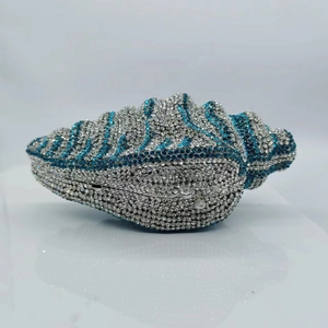 Detailed close-up of a silver and blue conch shell clutch bag with luxury rhinestones