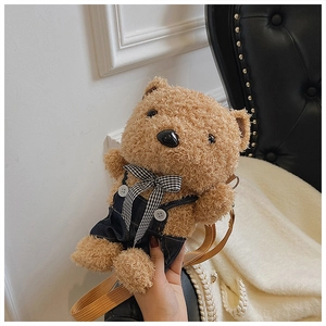 Detail of cute brown plush bear crossbody bag wearing denim overalls and a checkered bowtie