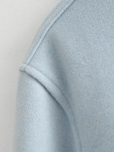 Close-up of the shoulder seam on a light blue wool blend coat showing fabric texture