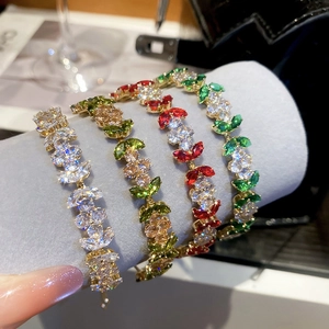 Detail view of four floral bracelets with green and white marquise-cut zircons in metal