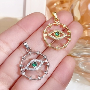 Macro shot of gold and silver plated evil eye charm pendants with green zircon stones