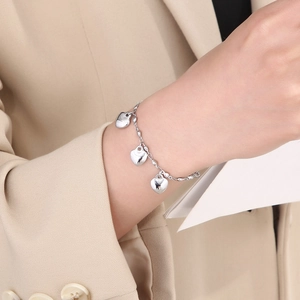 Elegant silver bead bracelet with three heart pendants worn on woman wrist