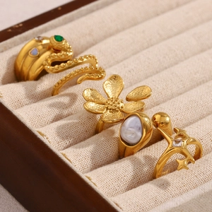 Macro view of five retro 18K gold plated rings with pearls and star motifs on linen display