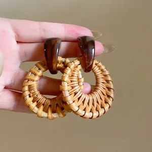 Detail showing retro handmade fan-shaped raffia woven hoop earrings with resin studs