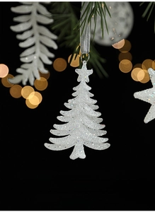 Sparkling white Christmas tree ornament with silver glitter on pine branch bokeh