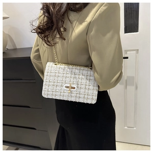 Detail of white tweed crossbody bag with gold thread texture and metallic chain strap