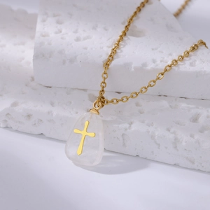 Detail of a gold cross embedded in a crystal pendant on a white stone background